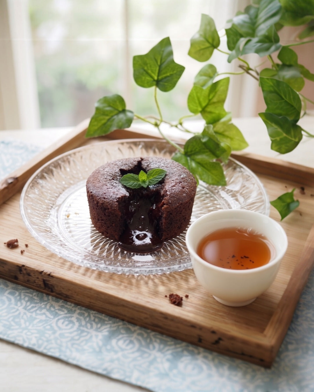 Thé hojicha Shôbi accompagné d'un fondant au chocolat, accord mets-thé sur plateau en bois avec feuillage