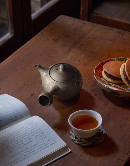 Théière et tasse de thé hojicha Shôbi sur table en bois, ambiance chaleureuse avec livre et biscuits