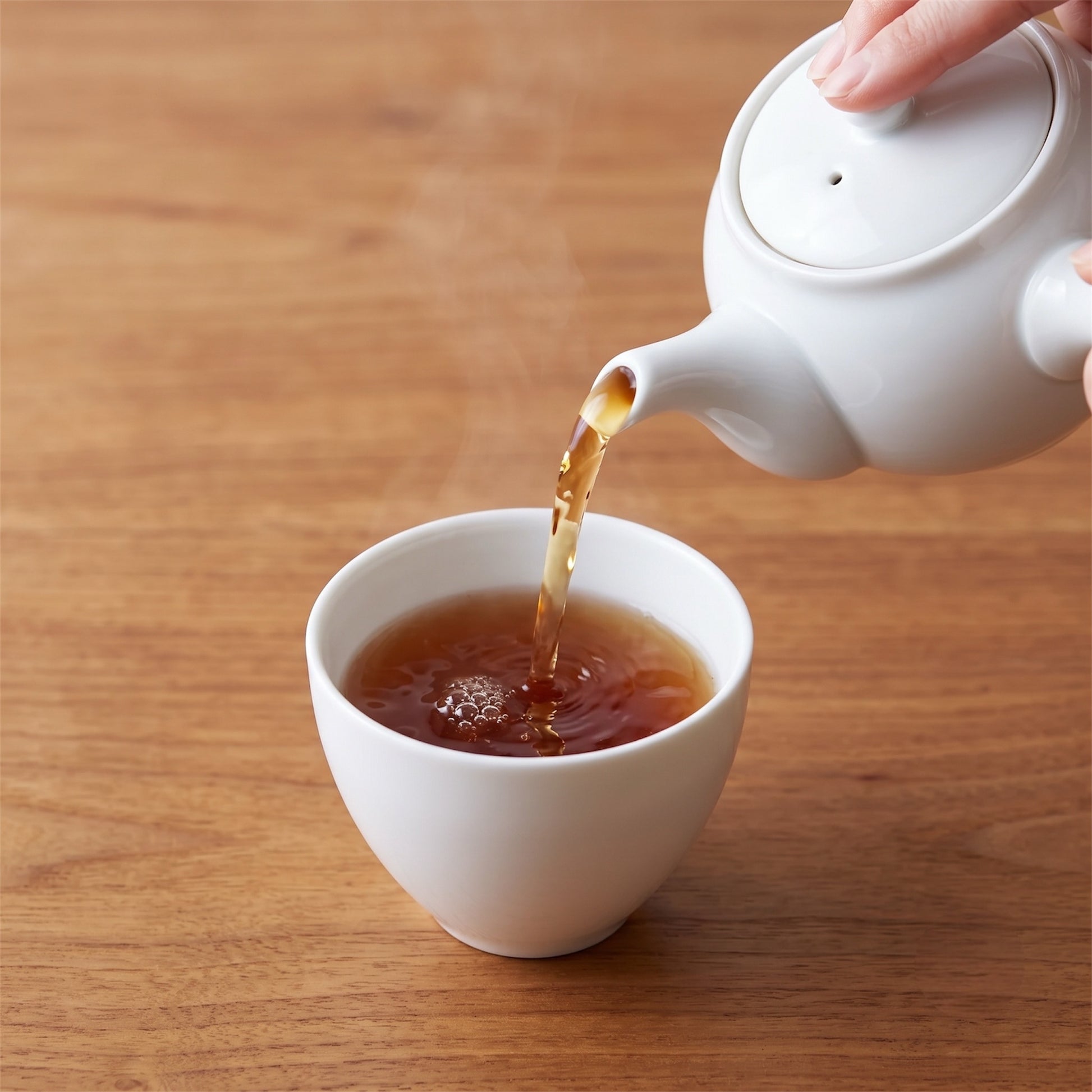 Thé hojicha japonais Shôbi versé depuis une théière blanche dans une tasse en céramique