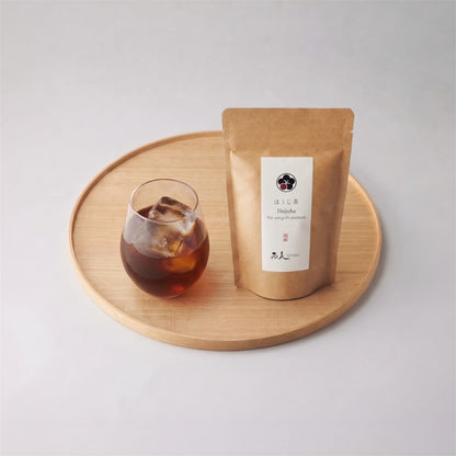 Thé hojicha glacé Shôbi servi dans un verre, présenté sur un plateau en bois avec le sachet