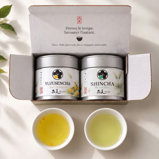 Coffret de thé japonais Shôbi ouvert avec deux boîtes de Sencha Yuzu et Shincha Seisui, accompagnées de deux tasses de thé vert.